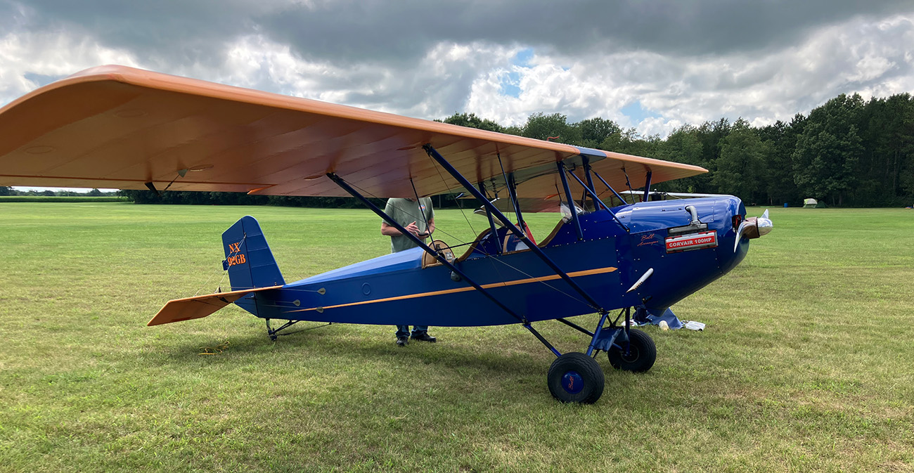 blue corvair on grass with cloudy skies