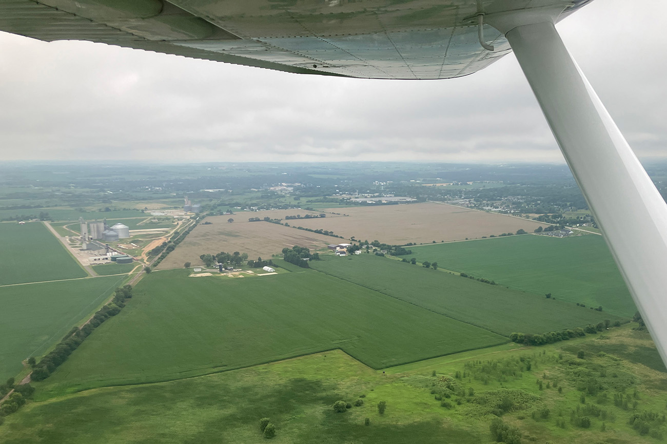 aerial view of farmland and underside of plane wing