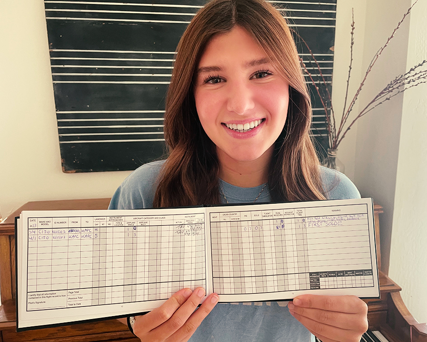 scholarship recipient holding up her log book after her solo
