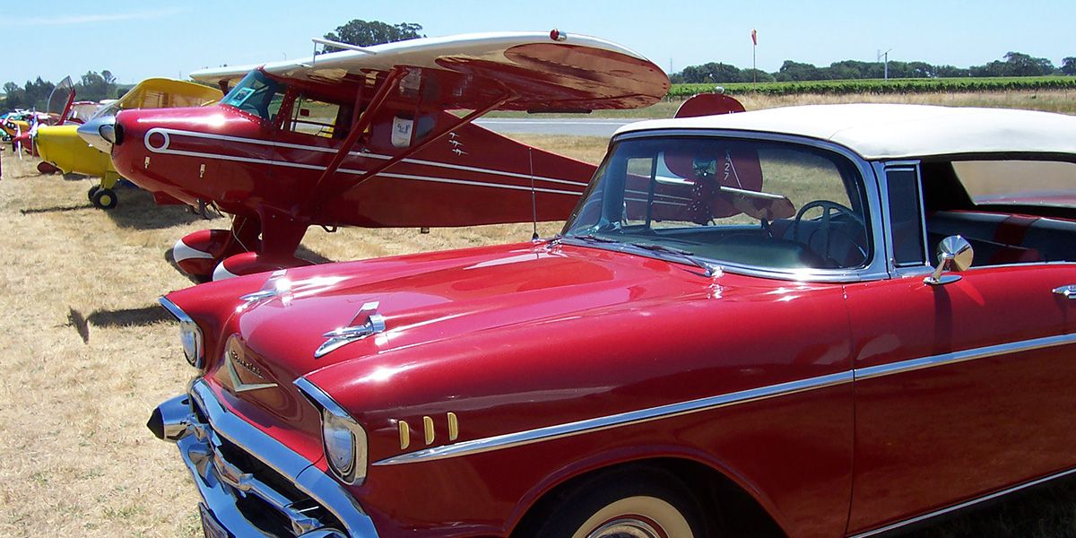 red vintage auto in front of red vintage plane